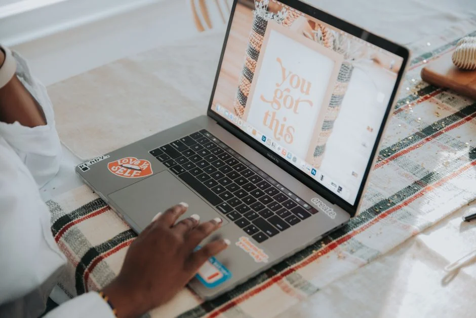 Person browsing the web on a MacBook at a wooden desk with a smartphone.